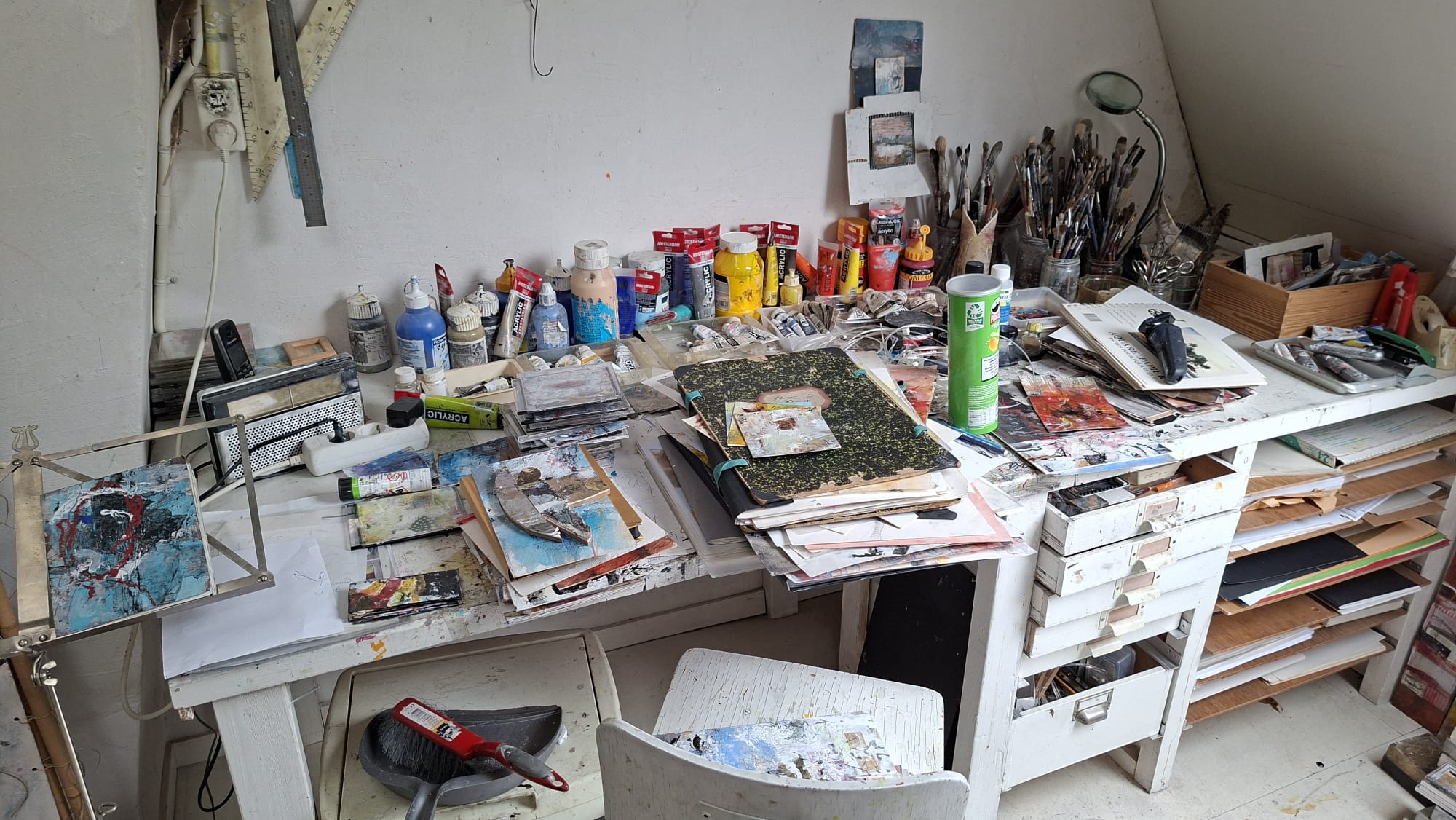 Werktafel vol verf, penselen en schetsboeken