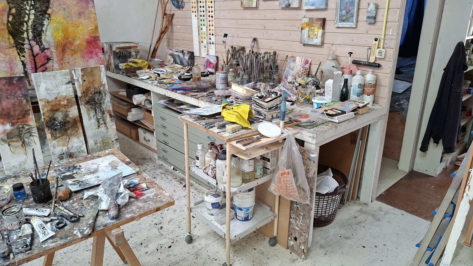 Overzicht van het atelier met grote abstracte schilderijen en werktafels